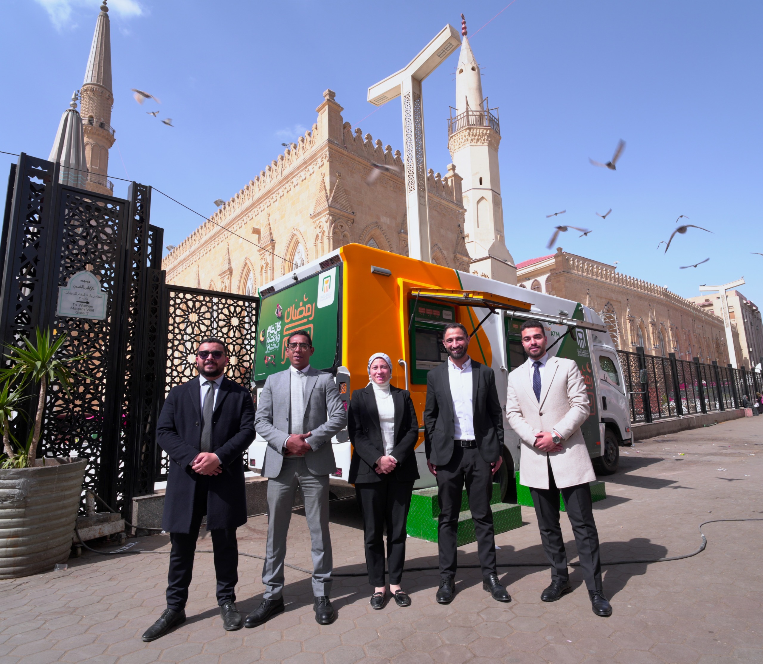 موظفو البنك الأهلي أمام إحدى مكاينات الصراف الآلي المتنقلة